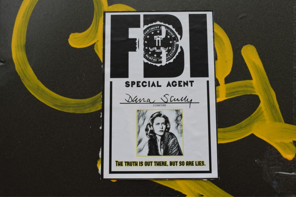 A photo of a fan-created black and white FBI badge, with a hand-drawn image of Dana Scully from the X-Files and a quote from her saying "the truth is out there but so are lies"